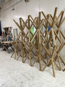 Stapel von naturbelassenen Holztischbeinen in einer Möbelwerkstatt, sorgfältig angeordnet zur Demonstration der handwerklichen Fertigung und Qualität.